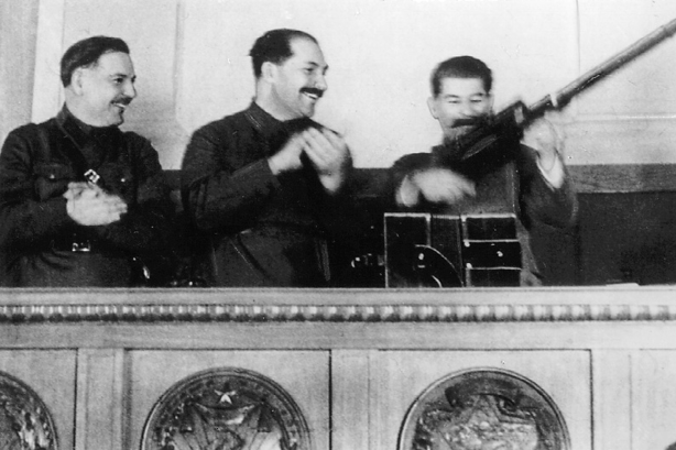 Stalin im Präsidium des siebzehnten Parteitags mit einem Gewehr, das ihm eine Arbeiterdelegation geschenkt hatte